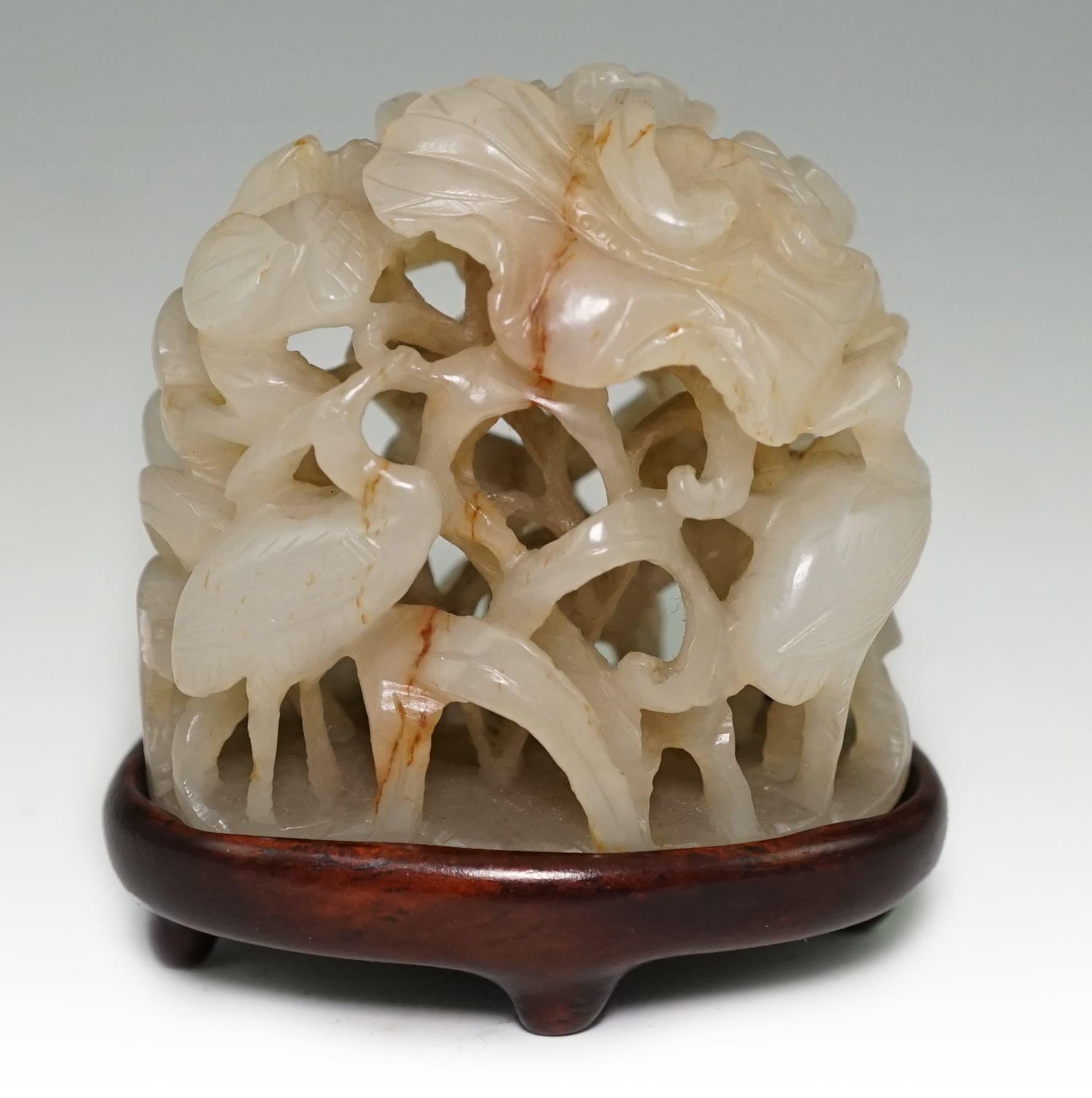 A Chinese pale celadon and russet veined jade ‘egret and lotus’ hat finial, Jin-Yuan dynasty